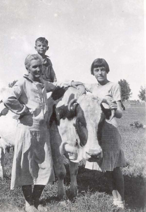 Young Frank sitting atop a cow with Bertha and Julia on either side