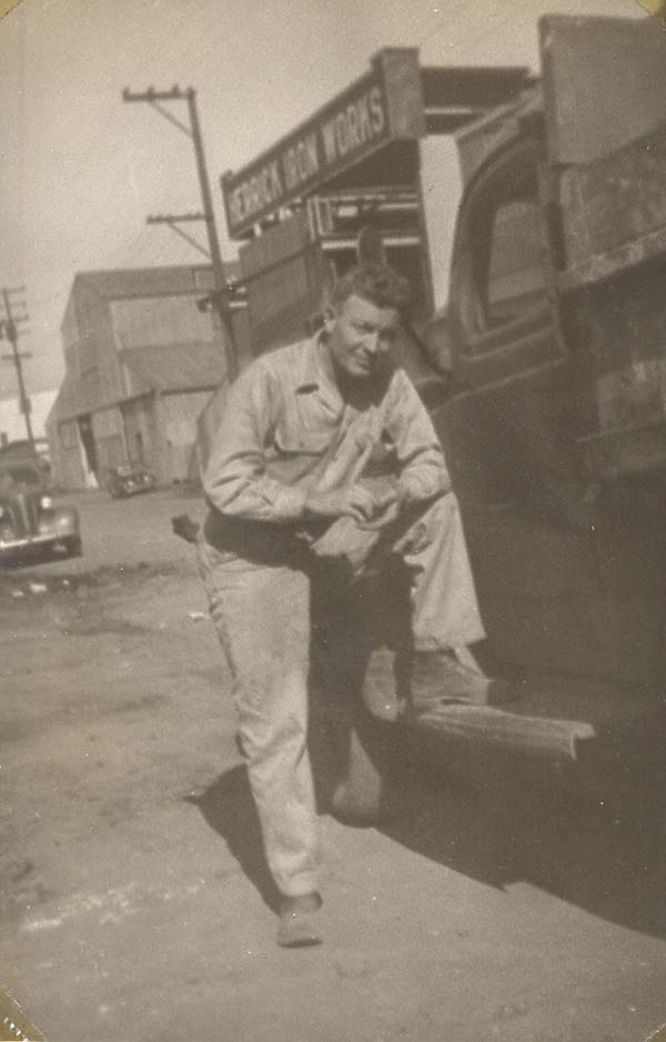 John with his leg propped up on a truck with a sign for Herrick Iron Works