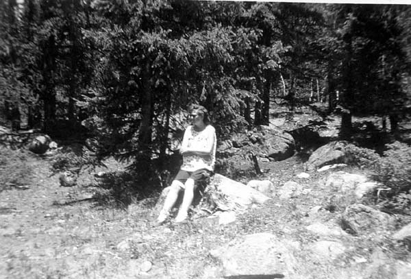 Alice (Troupe) Mahler, sitting on rock near the woods